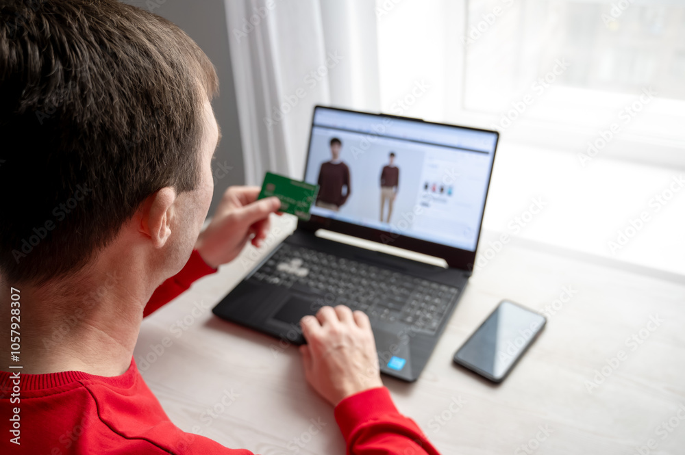 A man shopping online with a credit card on a laptop. Black Friday Sale
