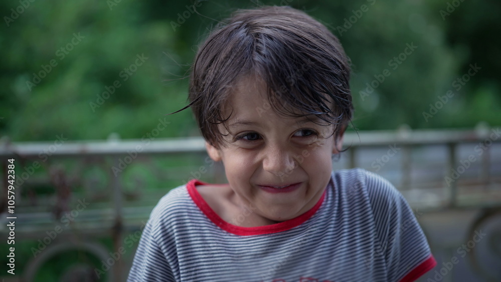 Young boy standing on a balcony, smiling directly at the camera, cheerful and happy moment of connection and joy, outdoor scene with natural greenery in the background Young boy standing on a balcony, smiling directly at the camera, cheerful and happy moment of connection and joy, outdoor scene with natural greenery in the background
