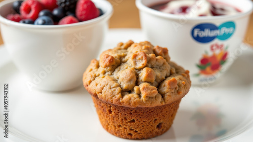 A muffin and two cups of berries on a plate.