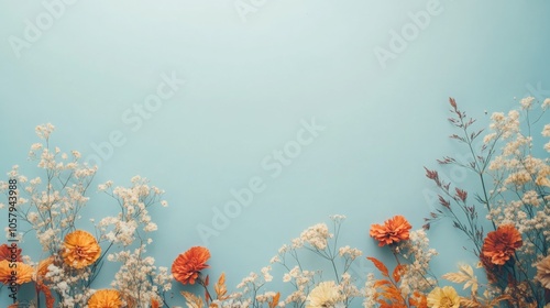 Fototapeta Naklejka Na Ścianę i Meble -  A flat lay of dried flowers against a light blue background. The flowers are a mix of white and orange, with some dried leaves.