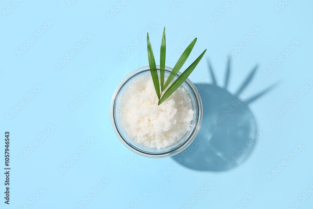 Glass jar with natural body scrub and palm leaf on color background Glass jar with natural body scrub and palm leaf on color background