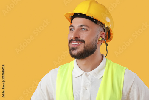 Male builder with earplugs on yellow background, closeup photo