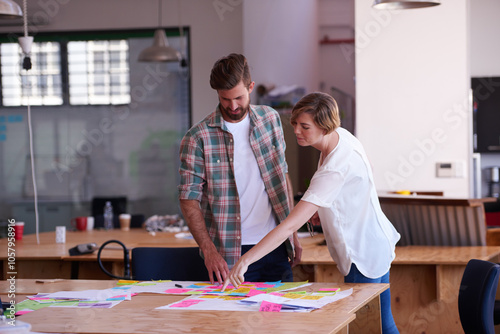 Woman, man and discussion with notes at startup for project, point or problem solving at media company. People, teamwork and reading with documents for mind map, process and review at creative agency