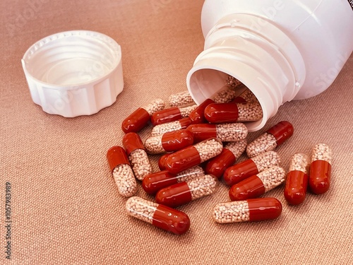 Obraz na płótnie Red and transparent medication capsules pouring from bottle containing pancreatic enzyme w salonie