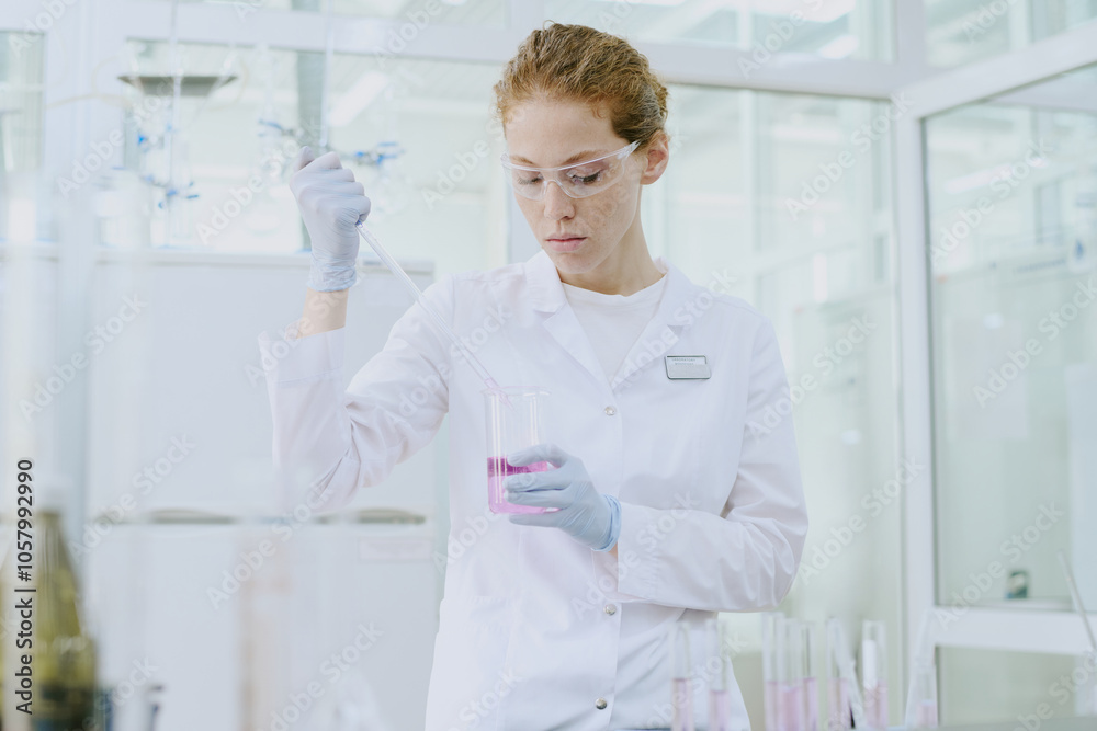 Scientist in laboratory coat and safety glasses conducting experiment with liquid in test tube. Surrounding area is filled with laboratory equipment and bright, clean environment Scientist in laboratory coat and safety glasses conducting experiment with liquid in test tube. Surrounding area is filled with laboratory equipment and bright, clean environment