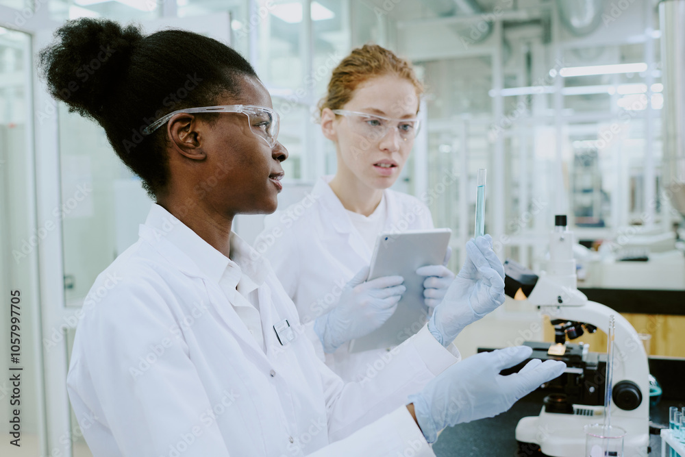 Scientists in laboratory coats performing examination using advanced equipment. Collaborative research environment with professionals wearing protective gear while analyzing data Scientists in laboratory coats performing examination using advanced equipment. Collaborative research environment with professionals wearing protective gear while analyzing data