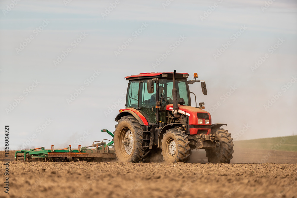 Farmer works the land, plowing a field with a modern red tractor on a sunny day Farmer works the land, plowing a field with a modern red tractor on a sunny day