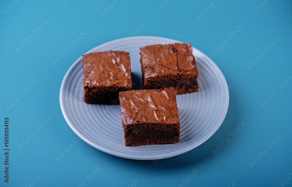 Dark chocolate brownie cakes in a plate on a blue background for Christmas holidays Dark chocolate brownie cakes in a plate on a blue background for Christmas holidays