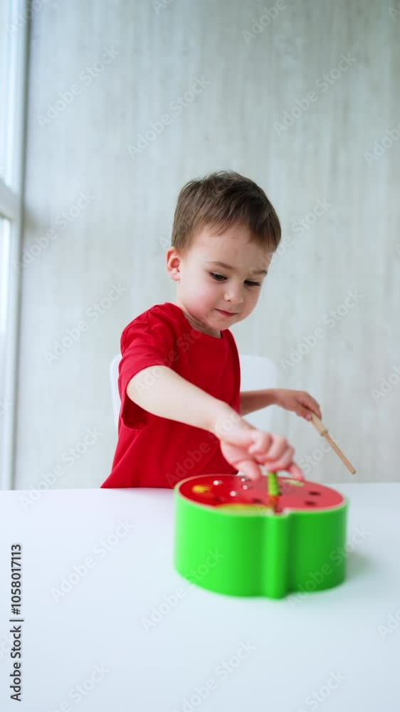 Focused Caucasian baby plays with a toy at home. Smiling toddler is busy with his educational toy. Vertical video. Focused Caucasian baby plays with a toy at home. Smiling toddler is busy with his educational toy. Vertical video.