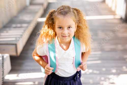 Happy little schoolgirl with school bag in school garden. Back to school outdoor