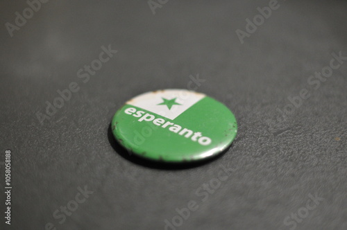 round flat esperanto pin laying on a gray counter