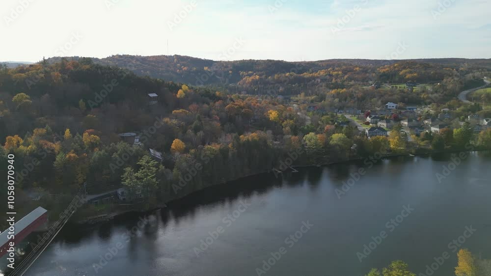 Aerial view of beautiful smooth green waters of a lake on a sunny autumn day. Bird's eye view of scenic emerald lake surrounded by forests and houses. Aerial view of beautiful smooth green waters of a lake on a sunny autumn day. Bird's eye view of scenic emerald lake surrounded by forests and houses.