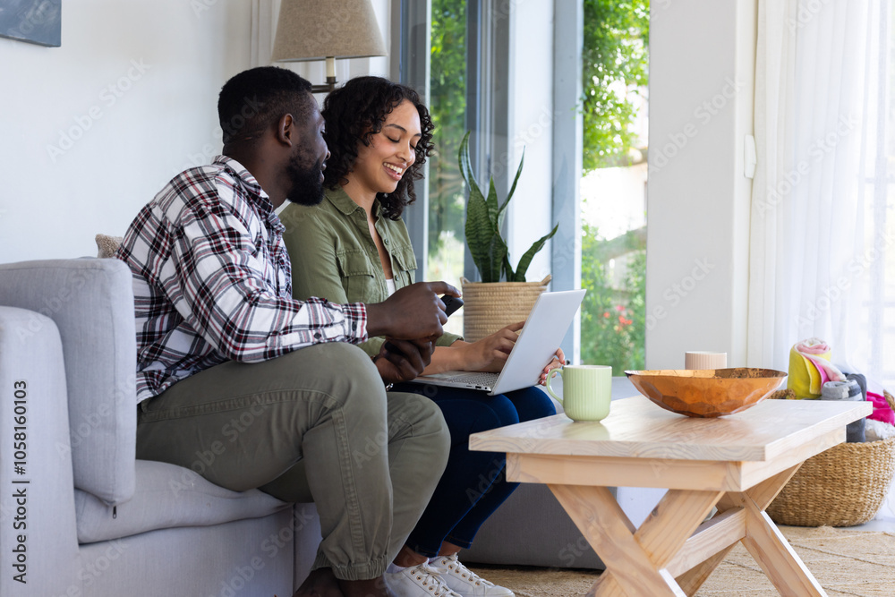 Happy multiracial couple using laptop together at home, enjoying cozy Thanksgiving moment Happy multiracial couple using laptop together at home, enjoying cozy Thanksgiving moment