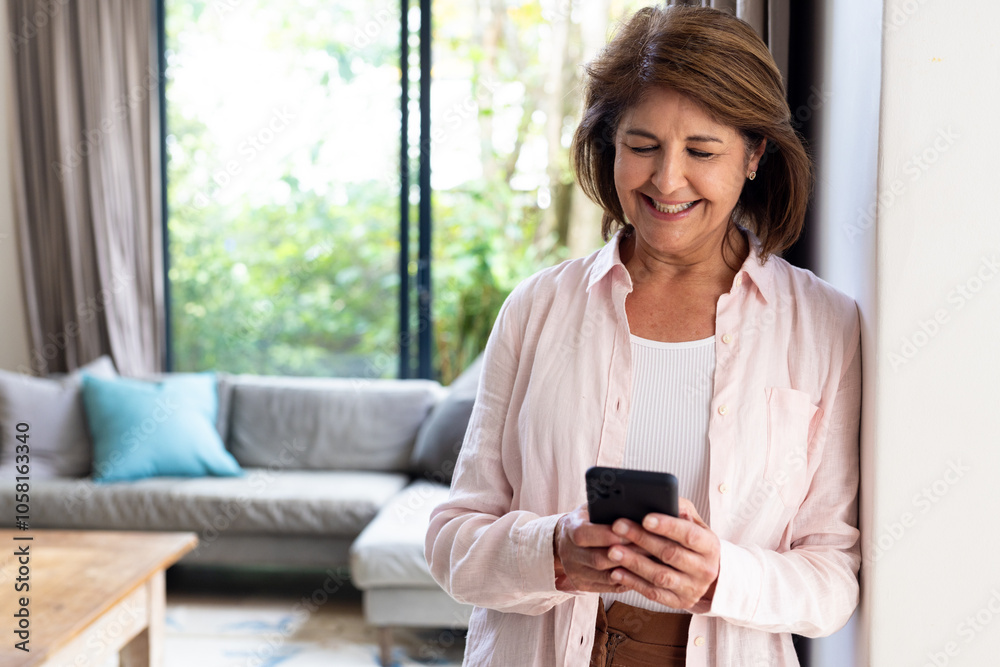 Smiling senior woman texting on smartphone at home, enjoying relaxed afternoon Smiling senior woman texting on smartphone at home, enjoying relaxed afternoon