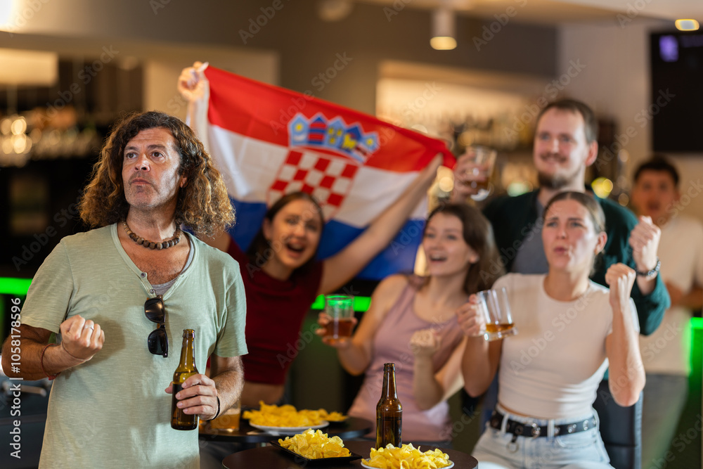 Fototapeta premium Group of friends fans watching match cheering with Croatian flag in bar