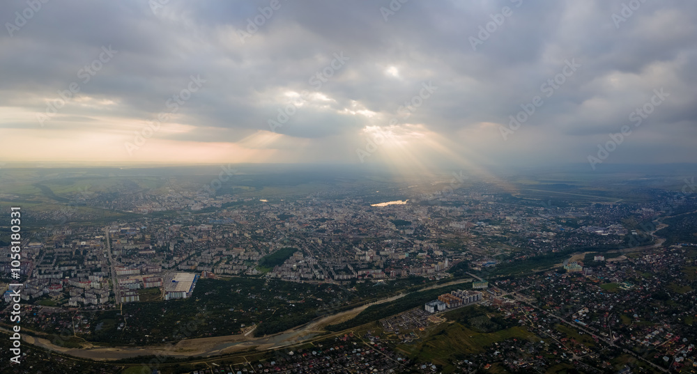 Aerial view from high altitude of distant city covered with puffy cumulus clouds flying by before rainstorm at sunset. Airplane point of view of landscape in cloudy weather Aerial view from high altitude of distant city covered with puffy cumulus clouds flying by before rainstorm at sunset. Airplane point of view of landscape in cloudy weather