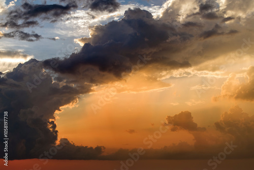 Bright sunset with setting sun behind vivid orange and yellow clouds