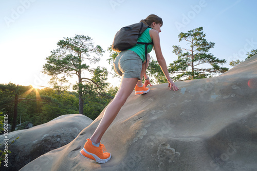 Hiker woman clambering on rocky mountain footpath in evening nature. Lonely female traveler traversing hard wilderness trail. Healthy lifestyle and sport concept photo