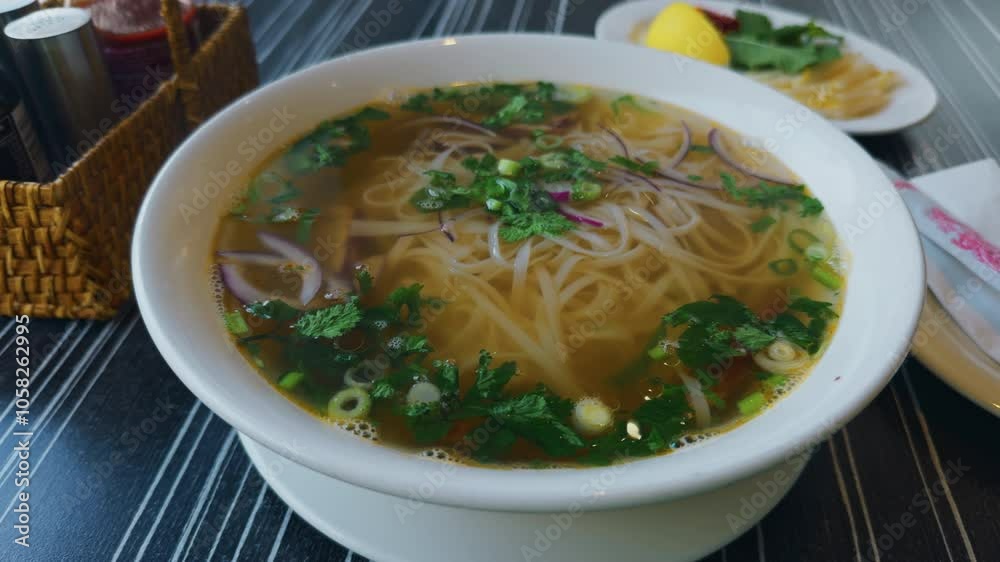Enjoy a delicious bowl of traditional Vietnamese Pho Noodle Soup, garnished with fresh herbs and lemon zest Enjoy a delicious bowl of traditional Vietnamese Pho Noodle Soup, garnished with fresh herbs and lemon zest