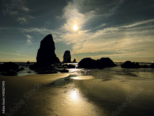 Landscape view of a dramatic sunset at Cannon Beach of a silhouette of a rock on the Oregon Coast; horizontal