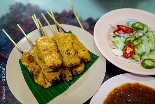 Satay sticks or barbecued pork meat with condiments during dinner at Hatyai, Thailand. photo