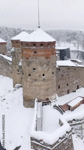 Vertical drone shot orbiting the tower on the Olavinlinna castle, winter in Finland photo