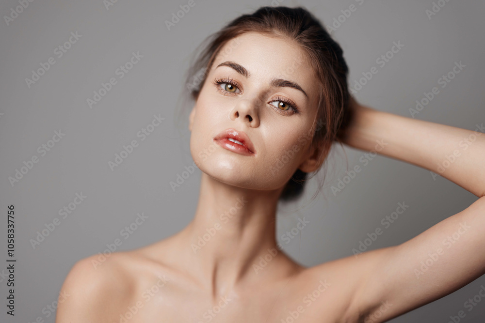 Beautiful young woman with hands on head posing on a gray background Beautiful young woman with hands on head posing on a gray background