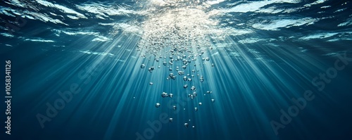 Underwater view with air bubbles floating upwards, beams of light penetrating the deep blue water, tranquil ocean background, peaceful atmosphere photo