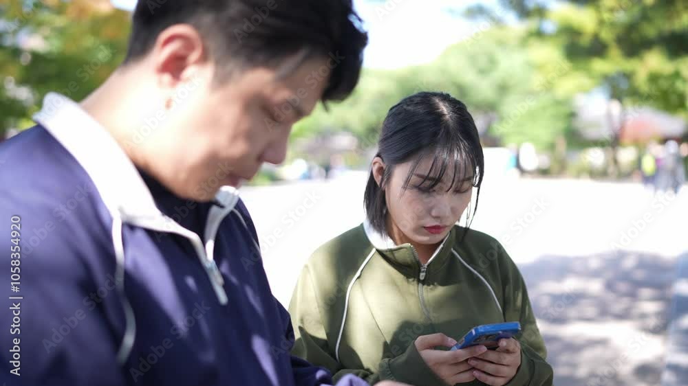 Korean couple, man in his 30s and woman in her 20s, wear jerseys and walk together in park with historical buildings in Seoul, South Korea. Korean couple, man in his 30s and woman in her 20s, wear jerseys and walk together in park with historical buildings in Seoul, South Korea.