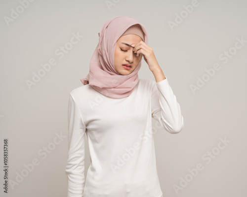 Unhappy young asian muslim woman hand touching head she's feeling depressed stress headache be tired standing on isolated white background. Muslim woman wearing abaya and hijab has office syndrome. photo