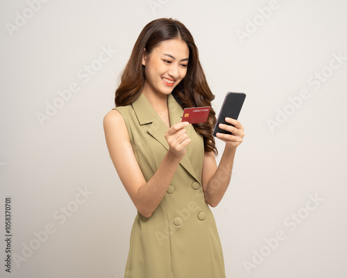 Portrait beautiful asian women standing pose holding credit card and smartphone to shopping payment. Attractive Happy businesswoman input the serial number of credit card cell phone financial photo