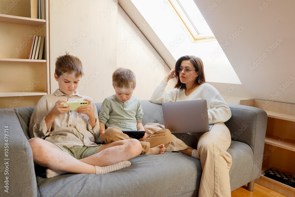 Two boys with pigmentation are sitting on the sofa with their mother Two boys with pigmentation are sitting on the sofa with their mother