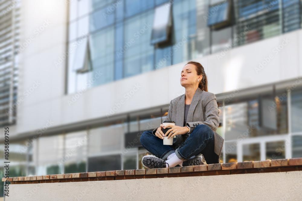 Female office worker resting in lotus pose on a bench outdoors during her coffee break. Work-life balance. Female office worker resting in lotus pose on a bench outdoors during her coffee break. Work-life balance.
