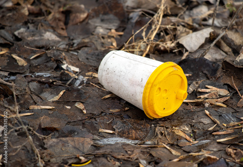 A white cup with a yellow lid is laying on the ground