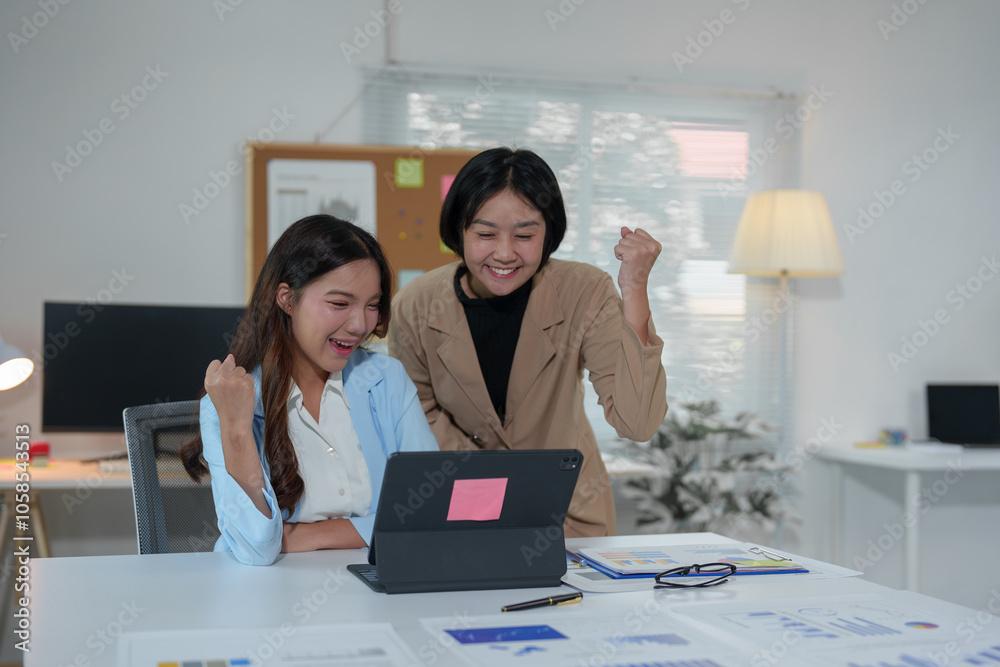 Two Asian businesswomen use laptops and smartphones in an open space office. Business concept. Data analysis, roadmap, marketing, accounting, auditing.