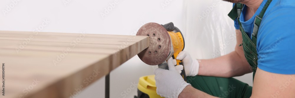 Concentrated worker polishes board edge with grinding tool