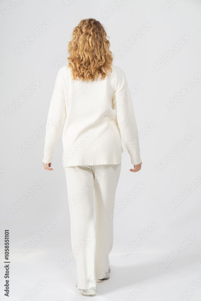 Attractive young blonde girl stands with her back on a white background, copy space Attractive young blonde girl stands with her back on a white background, copy space