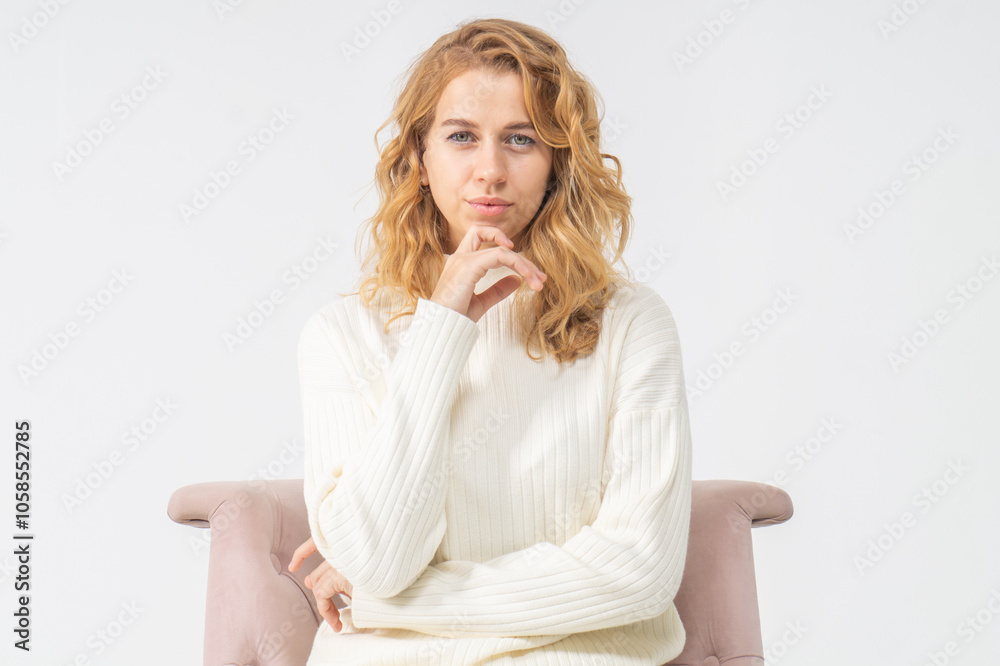 Attractive young blonde girl sits in a pink chair, white background, copy space Attractive young blonde girl sits in a pink chair, white background, copy space