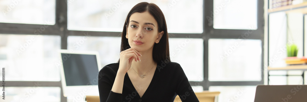 Pretty female worker looks forward at workplace in office Pretty female worker looks forward at workplace in office