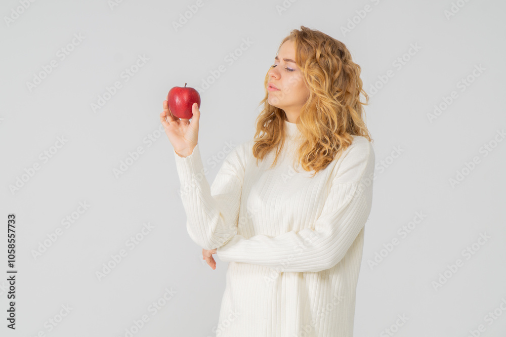 Happy attractive blonde young girl holding a red apple, white background, copyspace, bust portrait Happy attractive blonde young girl holding a red apple, white background, copyspace, bust portrait