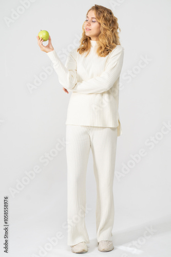 Happy attractive blonde young girl holding a yellow pear, white background, copyspace, full-length portrait