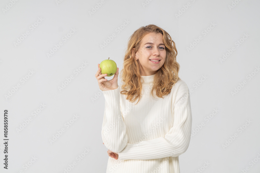 Happy attractive blonde young girl holding a green apple, white background, copyspace Happy attractive blonde young girl holding a green apple, white background, copyspace
