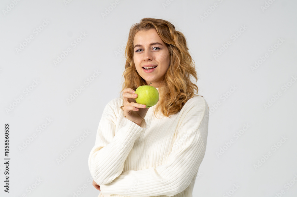 Happy attractive blonde young girl holding a green apple, white background, copyspace Happy attractive blonde young girl holding a green apple, white background, copyspace