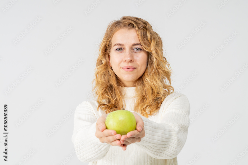 Happy attractive blonde young girl holding a green apple, white background, copyspace Happy attractive blonde young girl holding a green apple, white background, copyspace
