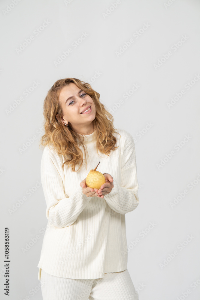 Happy attractive blonde young girl holding a yellow pear, white background, copyspace Happy attractive blonde young girl holding a yellow pear, white background, copyspace