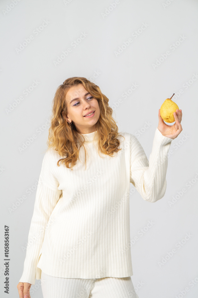 Happy attractive blonde young girl holding a yellow pear, white background, copyspace Happy attractive blonde young girl holding a yellow pear, white background, copyspace