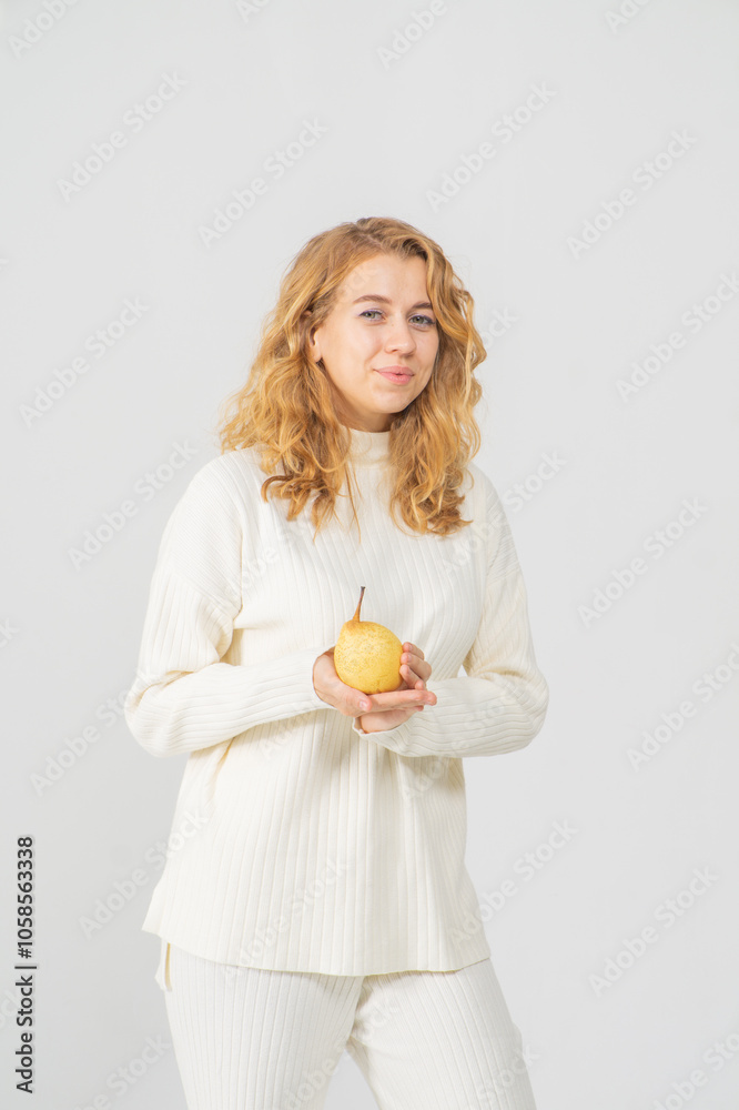 Happy attractive blonde young girl holding a yellow pear, white background, copyspace Happy attractive blonde young girl holding a yellow pear, white background, copyspace