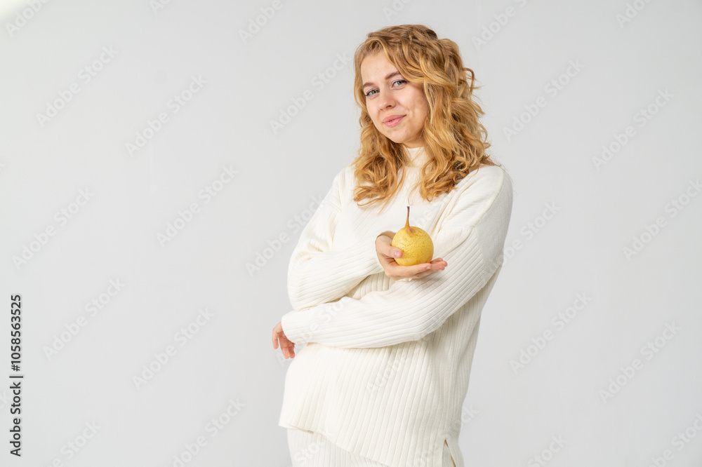 Happy attractive blonde young girl holding a yellow pear, white background, copyspace Happy attractive blonde young girl holding a yellow pear, white background, copyspace