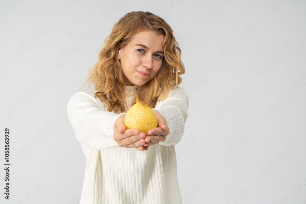 Happy attractive blonde young girl holding a yellow pear, white background, copyspace Happy attractive blonde young girl holding a yellow pear, white background, copyspace