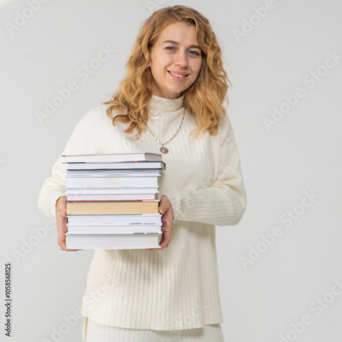 Cute young blonde girl with books in her hands, white background, copyspace